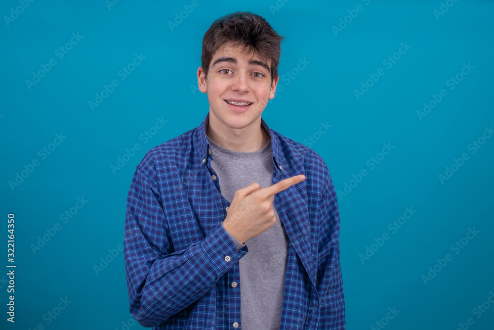 Wall mural expressive teenage young boy isolated on blue background