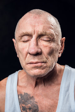 Portrait Of An Old Alcoholic Man With Closed Eyes On A Black Background