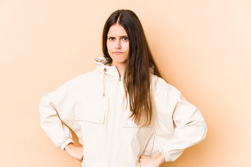 Young caucasian woman isolated on beige background confused, feels doubtful and unsure.