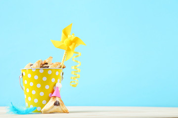 Purim holiday composition. Cookies with bucket and party supplies on blue background