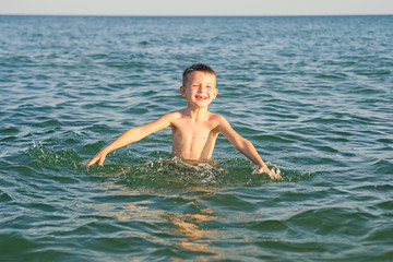 Happy child playing in the sea. Kid having fun outdoors. Summer vacation and healthy lifestyle concept