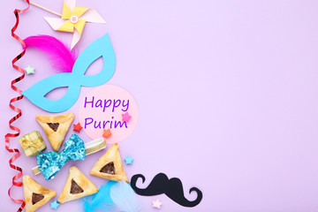 Purim holiday composition. Cookies with party supplies and text Happy Purim on purple background