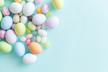 Happy Easter concept. Preparation for holiday. Easter candy chocolate eggs and jellybean sweets isolated on trendy pastel blue background. Simple minimalism flat lay top view copy space.