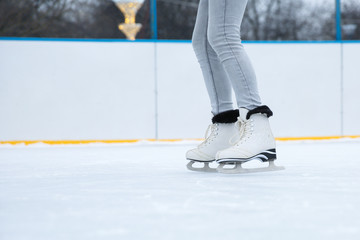 ice skating on the rink close up. white figure skates on woman's legs