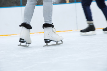 ice skating on the rink close up. white figure skates on woman's legs