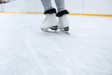 ice skating on the rink in motion close up. white figure skates on woman's legs