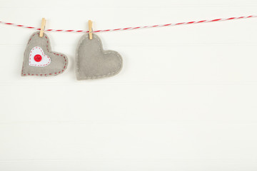 Fabric hearts with clothespins hanging on white wooden background