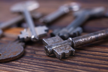 Several old keys to the lock on a wooden board close-up.