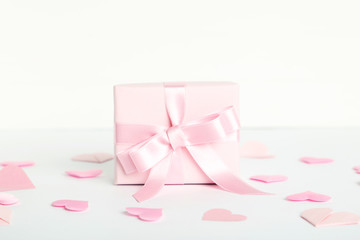 Gift box with ribbon and pink hearts on white background