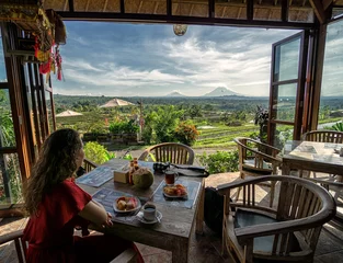 Poster Im Rahmen Young brunette girl having breakfast with view over the Jatiluwih rice terrace from open restaurant on Bali, Indonesia  © Donald