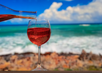 crystal glass in which an orange cocktail is poured. In the background beach . Summer vacation atmosphere.