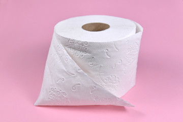 Roll of white toilet paper on pink background