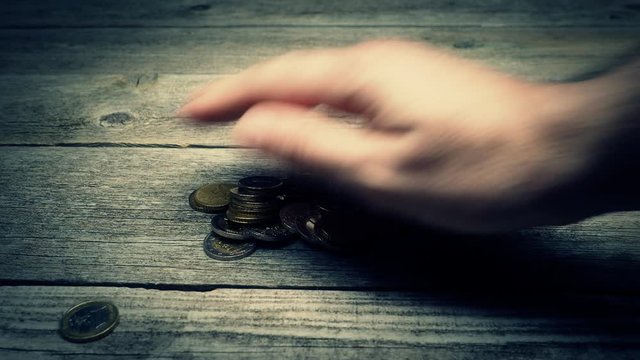 Hand giving money - Euro coins - on the wooden table. Another hand is taking money. Bribing concept. Studio shot. 4K VIDEO