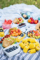Summertime picnic setting on the grass with open picnic basket, fruit, salad and cherry pie