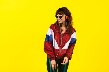 Cheerful gorgeous girl in clothes in the style of the 90s, with a vintage cassette player and...