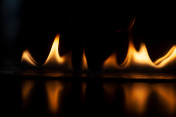 Naklejka premium Fiery background. Flames of fire in the dark. Flame texture. Tongues of fire rise smoothly. A simple background of yellow shades. Burning gel for ignition. Ignition of vapors. Fire is danger.
