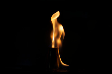 Alcohol burns on a stack for alcoholic drinks. Tongues of flame around a metal cup. Texture of fire. Yellow fire on a black background. Fire at the bar. The tradition of setting fire to alcohol.