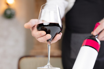 Close up of waiter holding glass and bottle of wine.