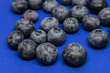 Scattered fresh blueberries (Vaccinium myrtillus) on a blue blackground, common bilberry or blue whortleberry closeup - Image