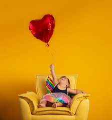 Cute cupid with red heart shape ballon on yellow background. Happy Valentine's Day. Children's Day. Carnival. Matinee.