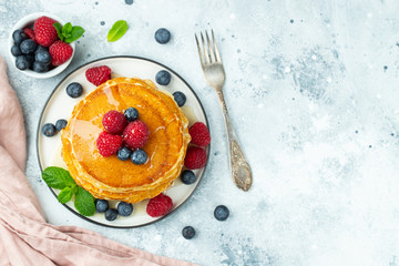 Close-up delicious pancakes, with fresh blueberries, raspberry's and honey on a light background. Top view with copy space