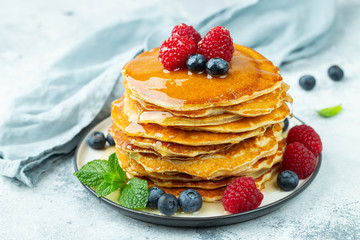 Close-up delicious pancakes, with fresh blueberries, raspberry's and honey on a light background