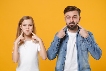 Funny bearded man in casual clothes with child baby girl. Father little kid daughter isolated on yellow background. Love family day parenthood childhood concept. Point index fingers on blowing cheeks.