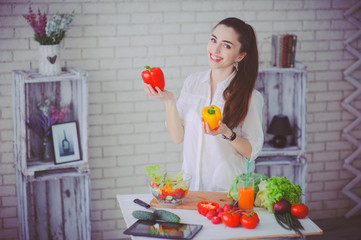 Pretty girl preparing fresh vegetable salad in her kitchen