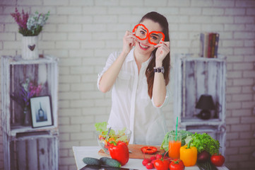 Pretty girl preparing fresh vegetable salad in her kitchen
