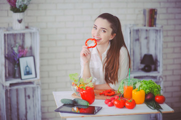 Pretty girl preparing fresh vegetable salad in her kitchen