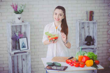 Pretty girl preparing fresh vegetable salad in her kitchen