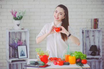 Pretty girl preparing fresh vegetable salad in her kitchen