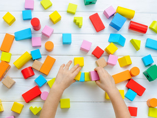 Kids hands playing with wooden toys on white background