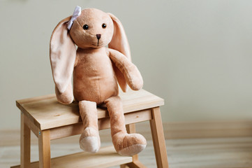 Kids soft toy rabbit with bow sitting on wooden chair