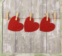 carved red paper hearts hanging on a brown rope, gray background
