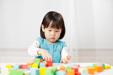 toddler girl playing creative toy blocks at home against white background