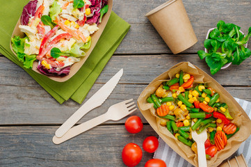 Steamed vegetables and vegetable salad in the kraft paper food containers on wooden background