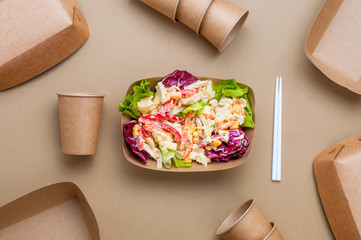 Vegetable salad in the brown kraft paper food containers near cups