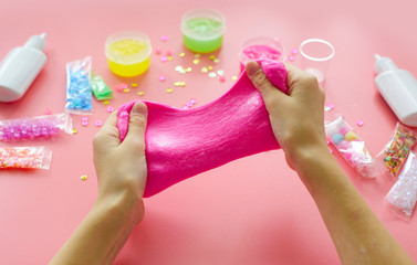 a girl making slime herself. child making slime on pink background.