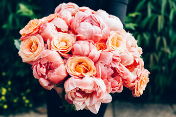 Woman in black dress is holding bunch of pink peonies and roses. Card Concept, pastel colors of flowers