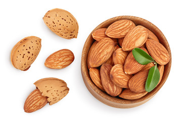 Almonds nuts with leaves in wooden bowl isolated on white background with clipping path and full depth of field. Top view. Flat lay.