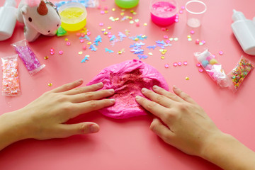 Obraz na płótnie Canvas a girl making slime herself. child making slime on pink background.