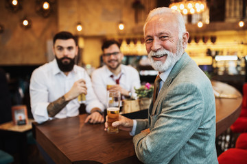  Three businessmen cheering while watching football match in a cafe bar.