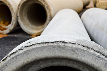 Large concrete stone cement sewer plumbing pipes of large diameter for the industrial construction of water supply or sewage at a construction site during the repair