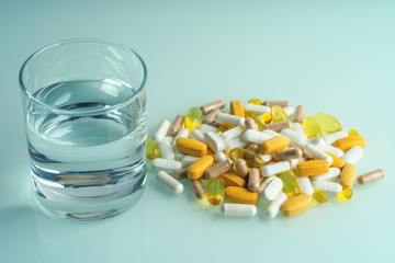 Medicaments, pill capsules, drugs and dietary supplements with water glass close up. Medication treatment concept.