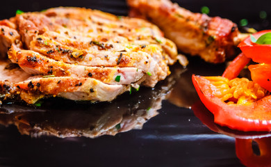 Meat slicing with tomatoes on a black dish