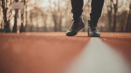 Young athlete preparing at start line and making starting. Single track and field sprinter in a stadium starting out. Close detail of track runner putting hands at starting line.