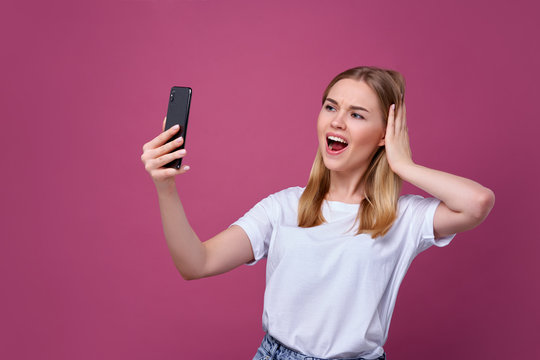 Taking picture. cheerful blond-haired woman doing selfie on isolated pink background