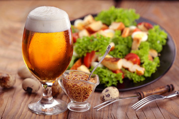 Glass of beer on wooden table. With salad caeser