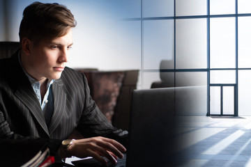 A young man is working at a computer against the background of an empty lobby of an office building. Irregular working hours. Execution of an urgent project. Search for tenants of premises.